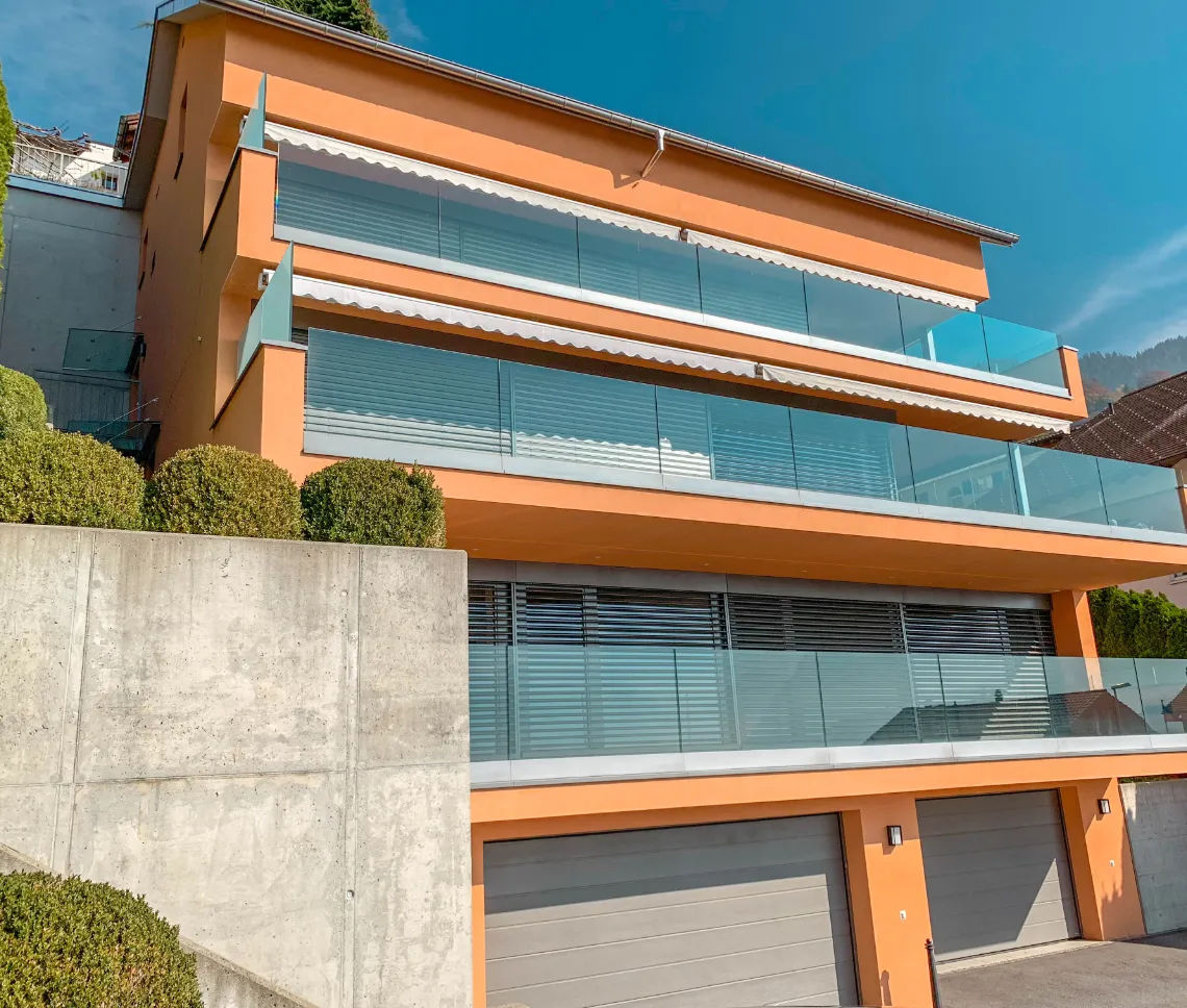 Ein Haus mit großem Garagenbereich und Balkon. Außenansicht der Maisonette-Wohnung Triesenberg.