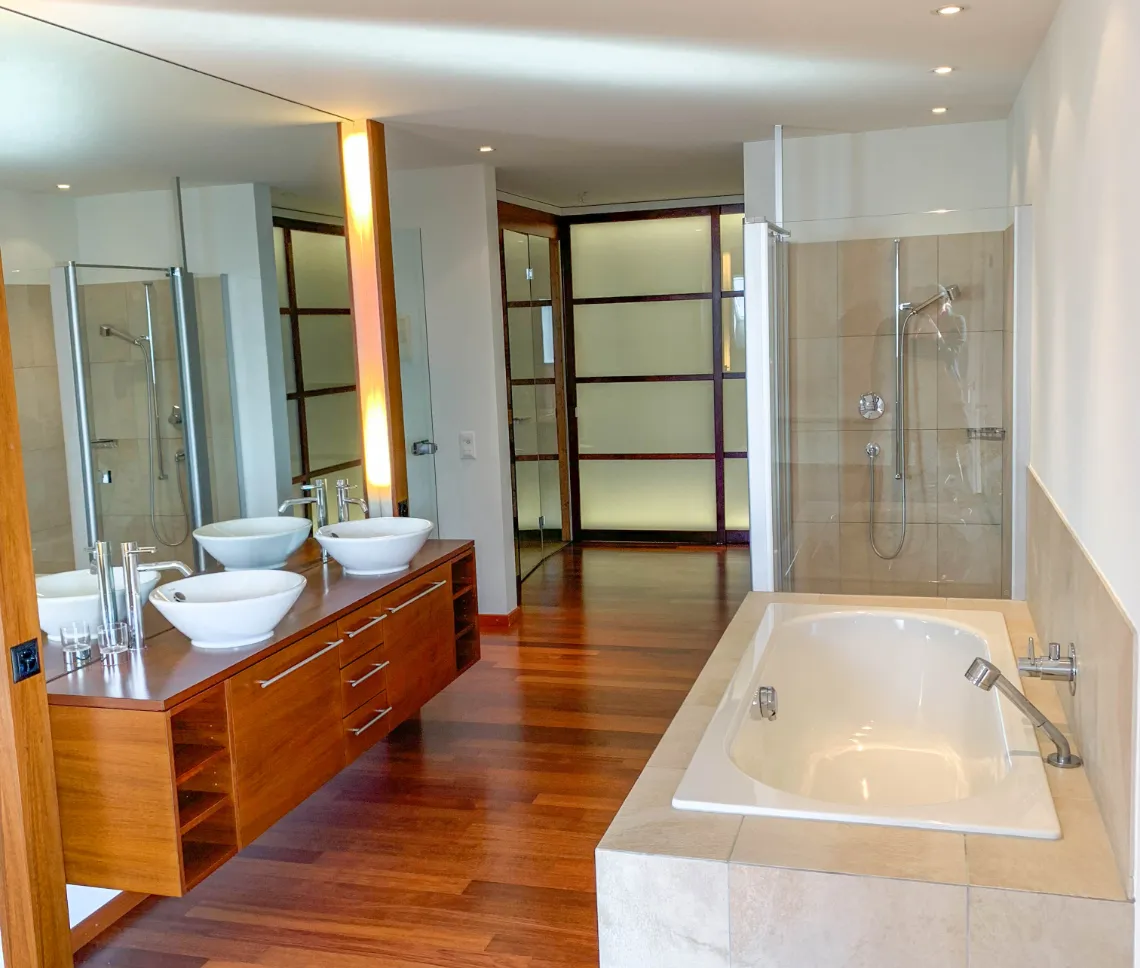 Badezimmer mit großem Spiegel und Badewanne, hell und modern eingerichtet.