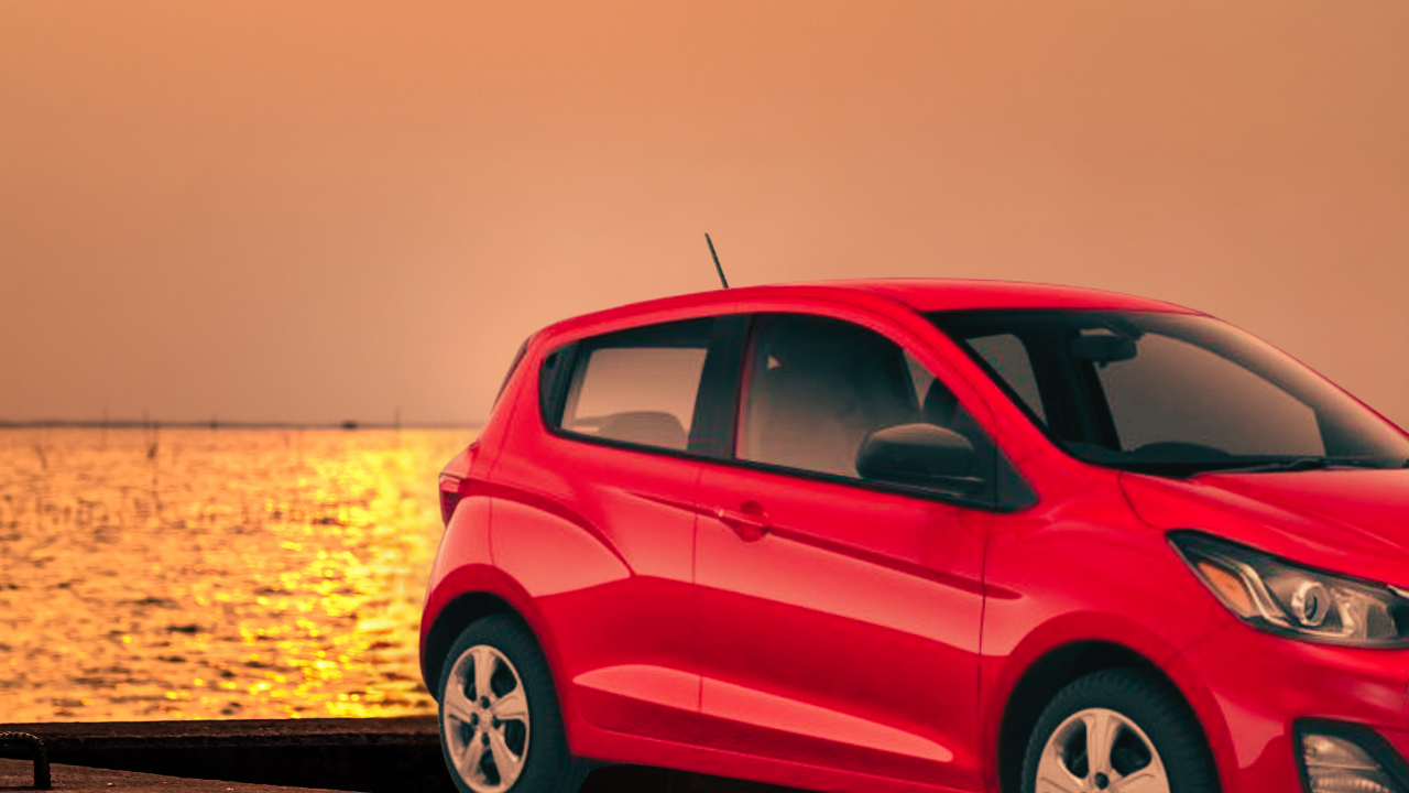 Red Chevrolet Spark parked at a beach