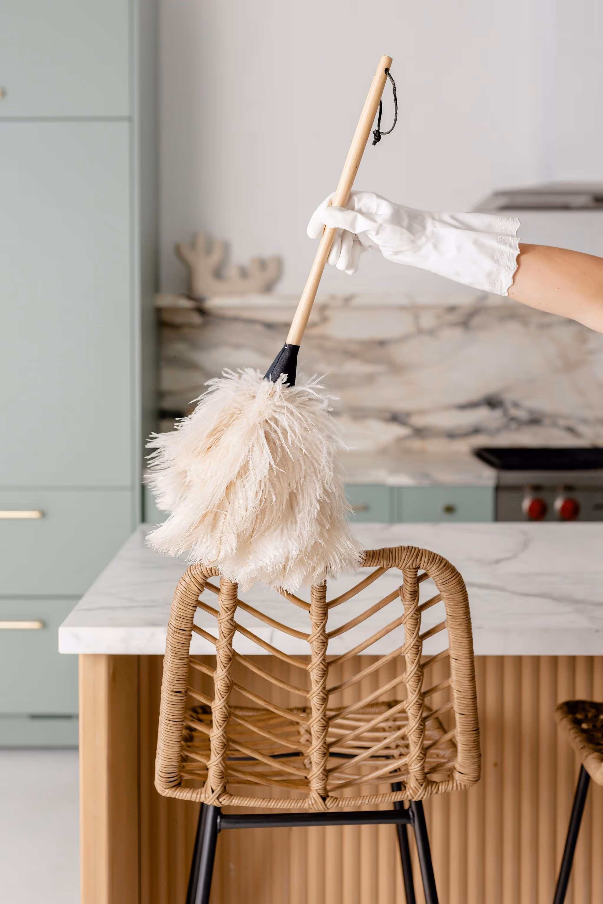 hero section image - an instance of a cleaning job, a hand dusting a wicker chair in a kitchen