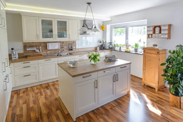 Helle Landhausküche mit Kücheninsel, Holzarbeitsplatten und gemütlichem Tageslicht-Ambiente.