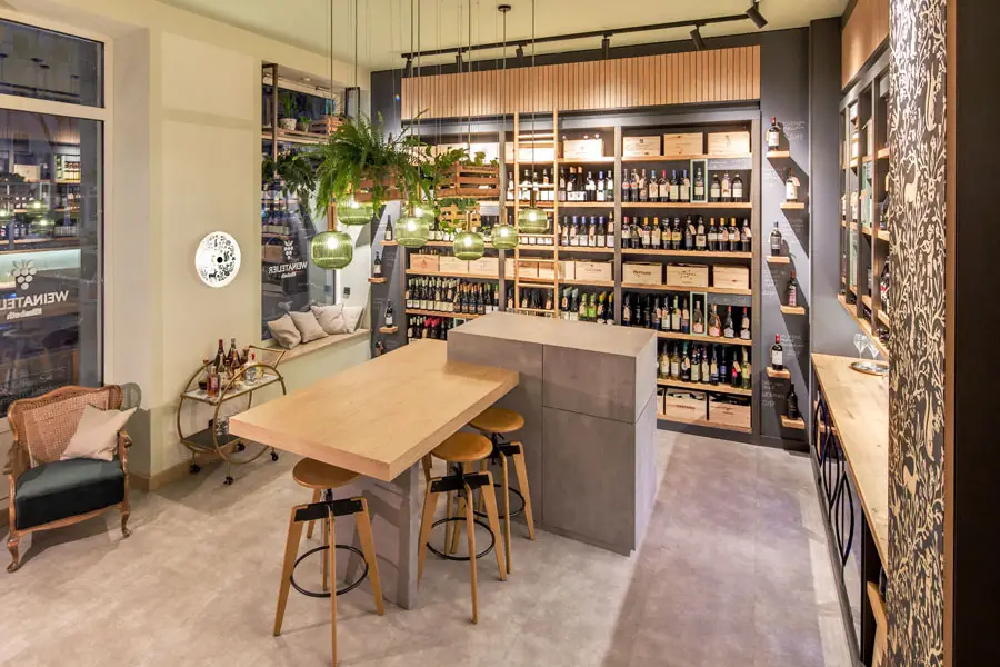 Modern eingerichtetes Weinatelier mit Holzregalen, stilvoller Beleuchtung und gemütlicher Sitzecke – exklusive Vinothek mit hochwertiger Innenarchitektur.