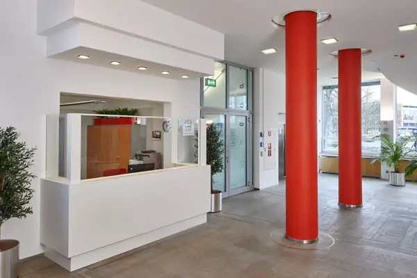 Moderne Empfangshalle im Abellio-Gebäude mit roten Säulen, Glasfront und heller Rezeption im Eingangsbereich.