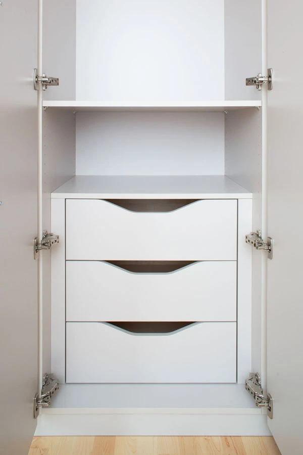 Einbauschrank mit drei grifflosen Auszugschubladen in Weiß, integriert in einen Hochschrank mit offenen Türen und sichtbaren Scharnieren.