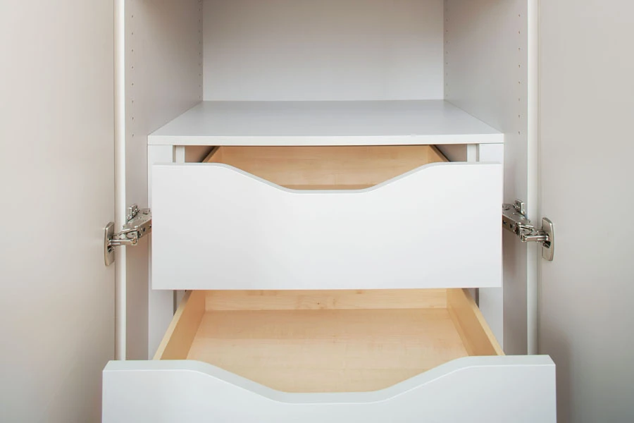 Innenansicht eines weißen Einbauschranks mit zwei grifflosen Auszugschubladen und seitlichen Topfscharnieren.