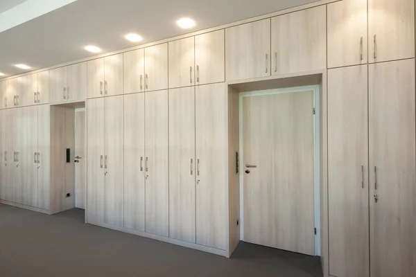 Büroeinbauschränke in heller Holzoptik mit durchgängiger Frontgestaltung und integrierten Türen für maximale Stauraumnutzung.