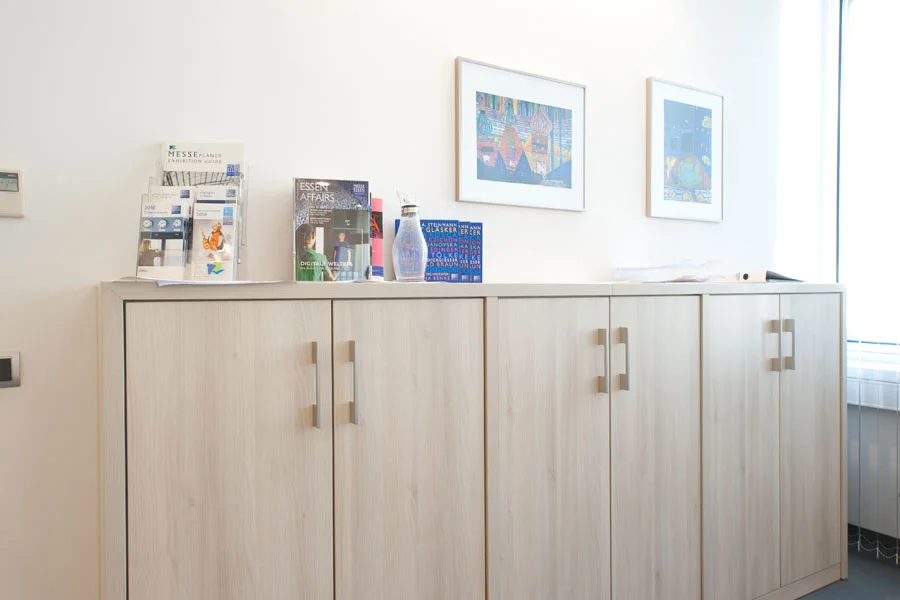 Niedrige Büroschränke aus hellem Holzdekor mit Broschüren und Magazinen, ideal für Wartebereiche oder Empfangsräume.