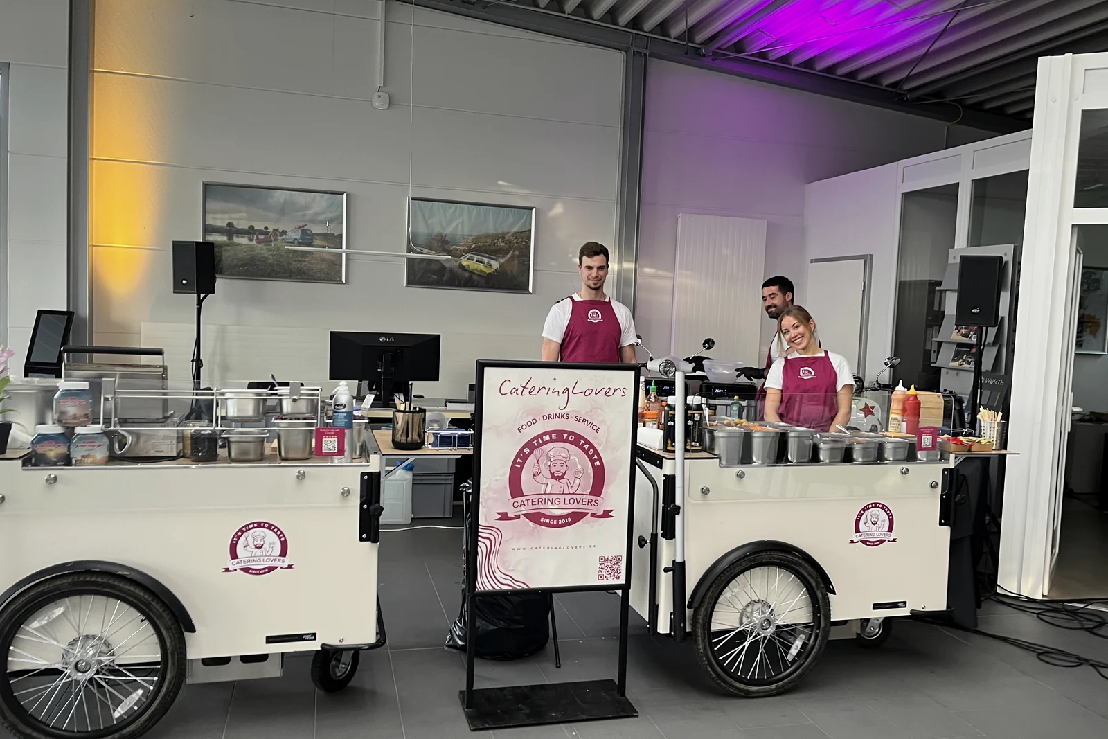 Zwei CateringLovers-Stationen mit Crew und Aufsteller in einem hellen Showroom bei einem Kundenevent