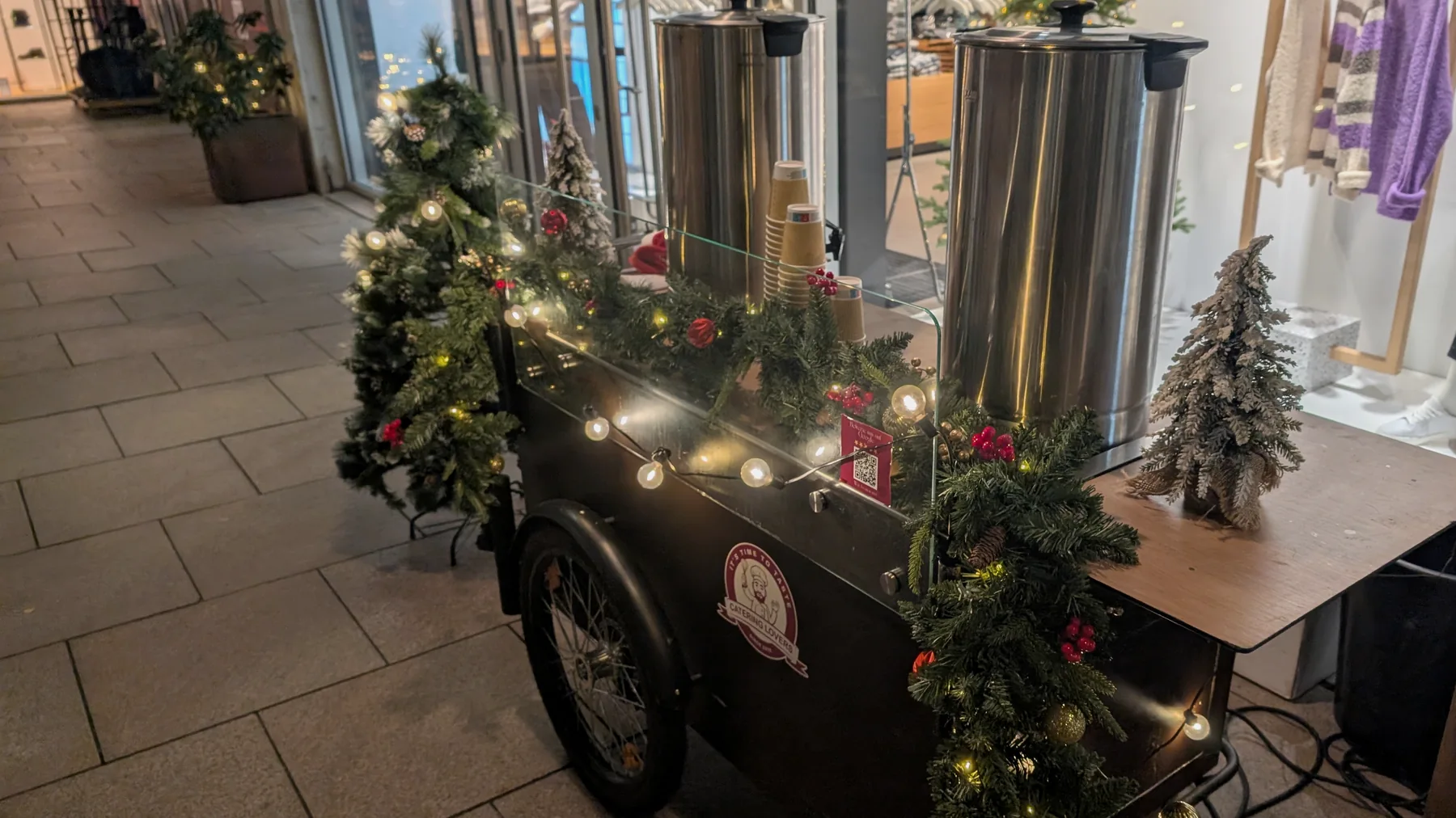 Weihnachtlich geschmücktes CateringLovers-HappyBike mit Tannengirlande, roten und goldenen Kugeln, Lichterkette und zwei Glühwein-Kesseln