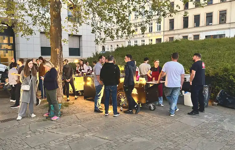 Gäste am Abend an zwei HappyBike-Stationen unter Lichterketten