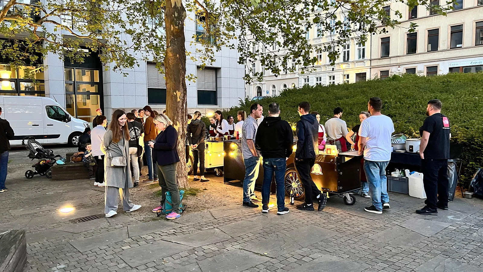 Gäste an der Live-Cooking-Station bei einem Stadtevent am Abend