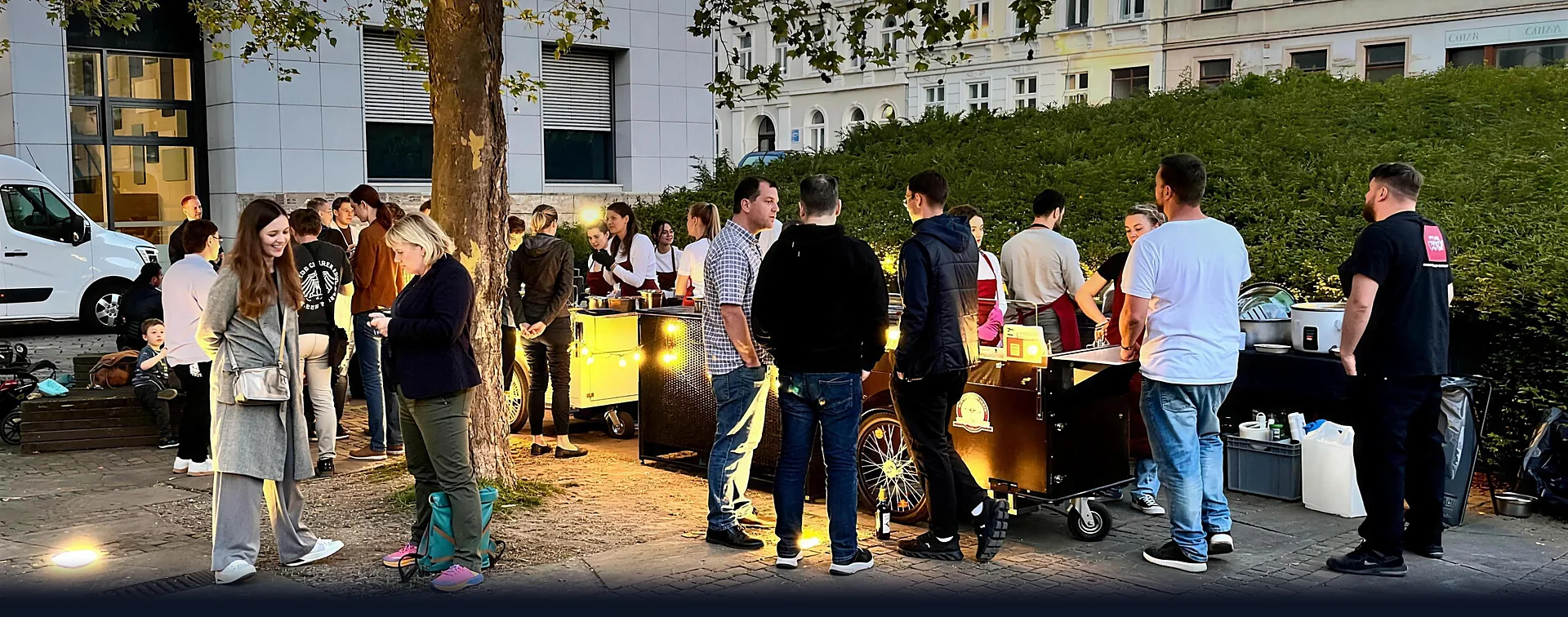 Grossveranstaltung am Abend: Gäste versammeln sich an beleuchteten HappyBike-Stationen im Stadtraum.