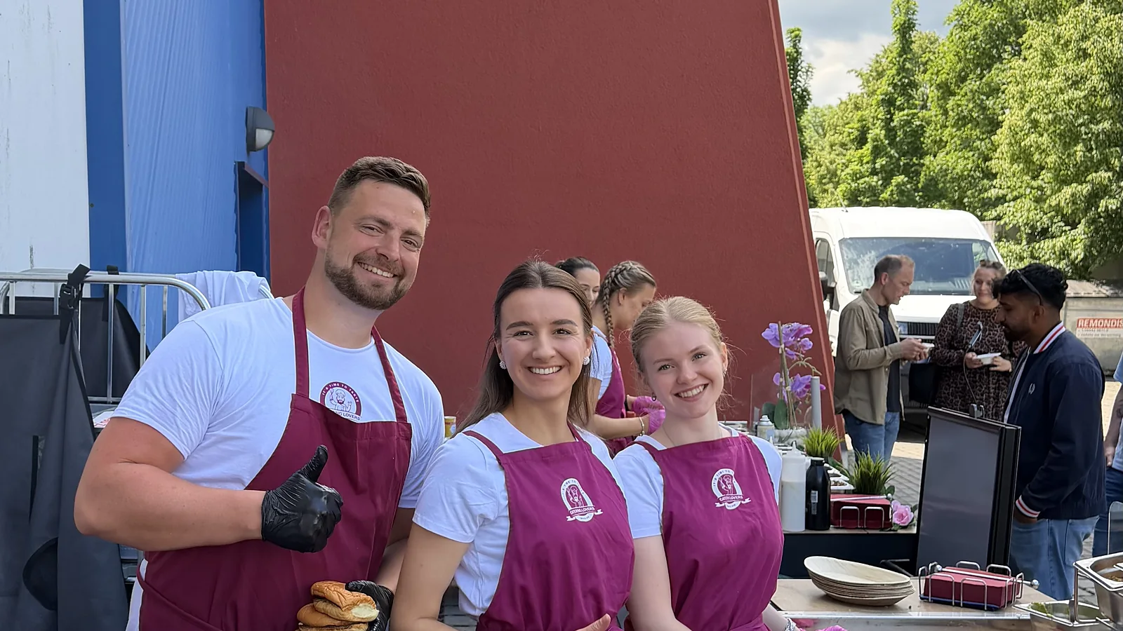 Drei Crew-Mitglieder am Griddle beim Straßenevent, frische Buns in der Hand