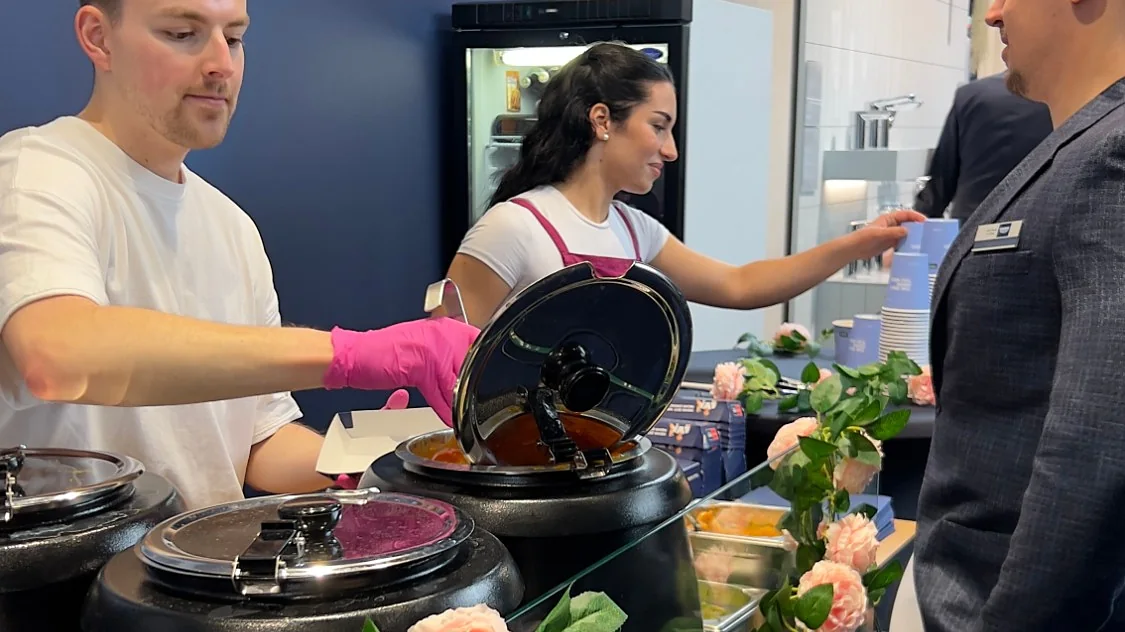 Messestand: Ausgabe eines warmen Gerichts aus dem Suppenkessel an einen Gast