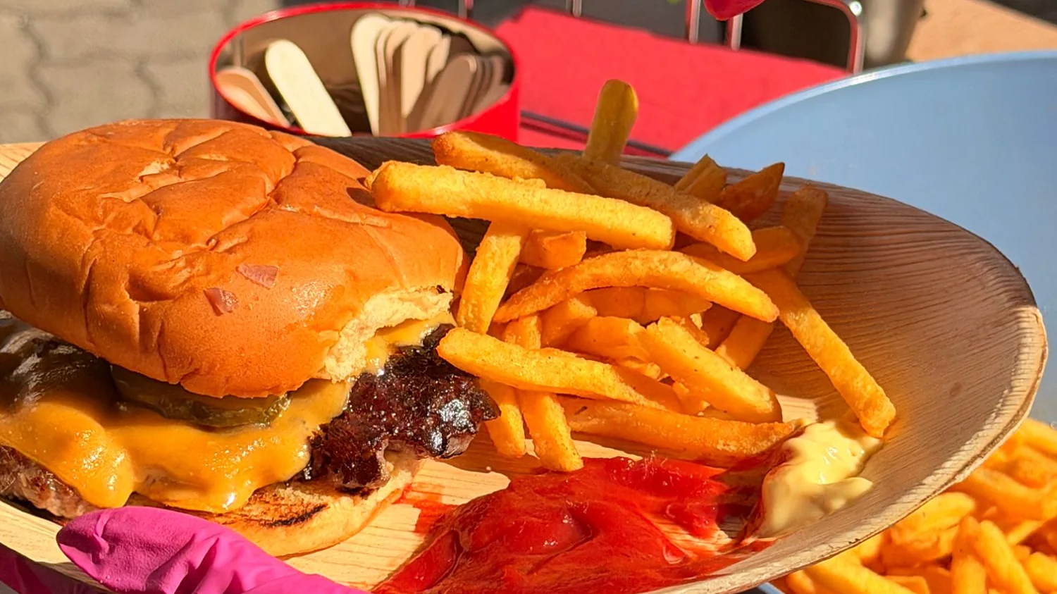 Cheeseburger mit Pommes und Dips auf dem Palmblatt-Teller
