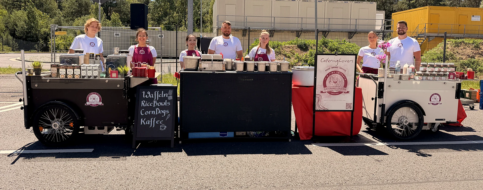 Roadshow-Aufbau: drei CateringLovers-Stationen in Reihe mit Kreidetafel, die Crew dahinter bereit für den nächsten Stopp.
