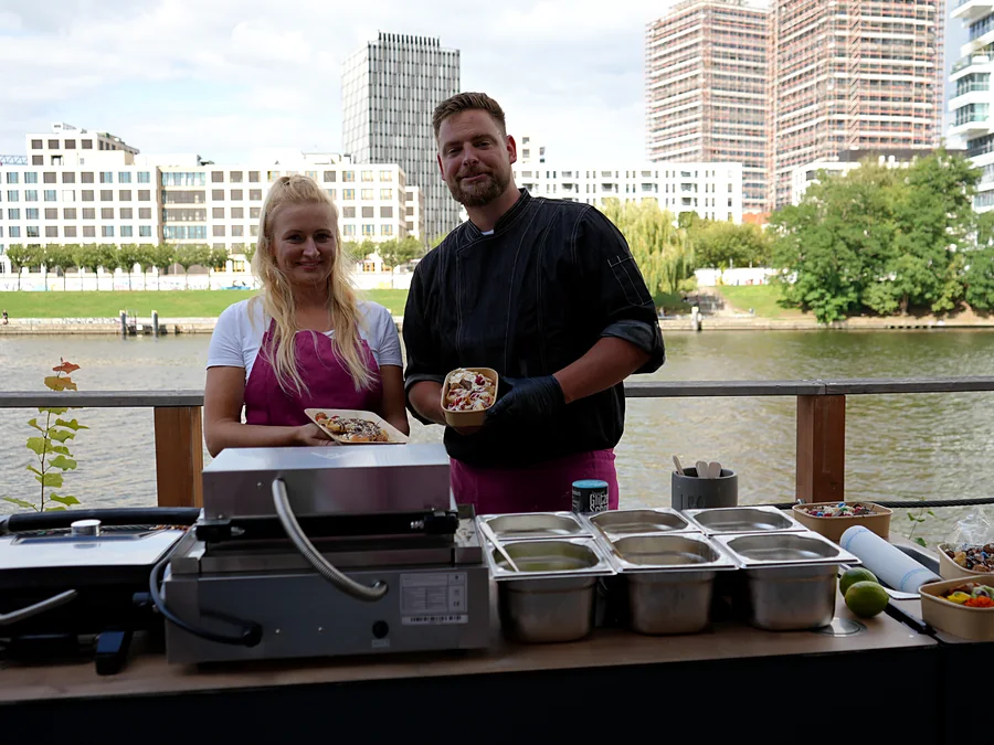 Zwei Crew-Mitglieder von CateringLovers zeigen frisch angerichtete Portionen an der Live-Cooking-Station