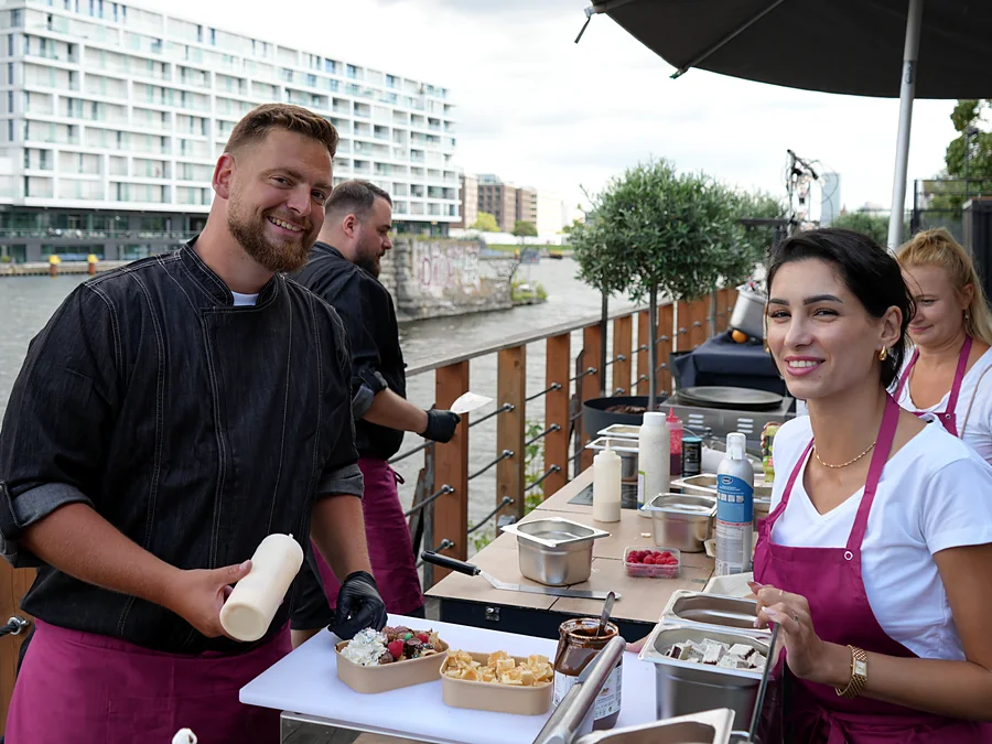 Crew von CateringLovers mit frisch angerichteten Waffel-Toppings an der Live-Cooking-Station unter dem Sonnenschirm