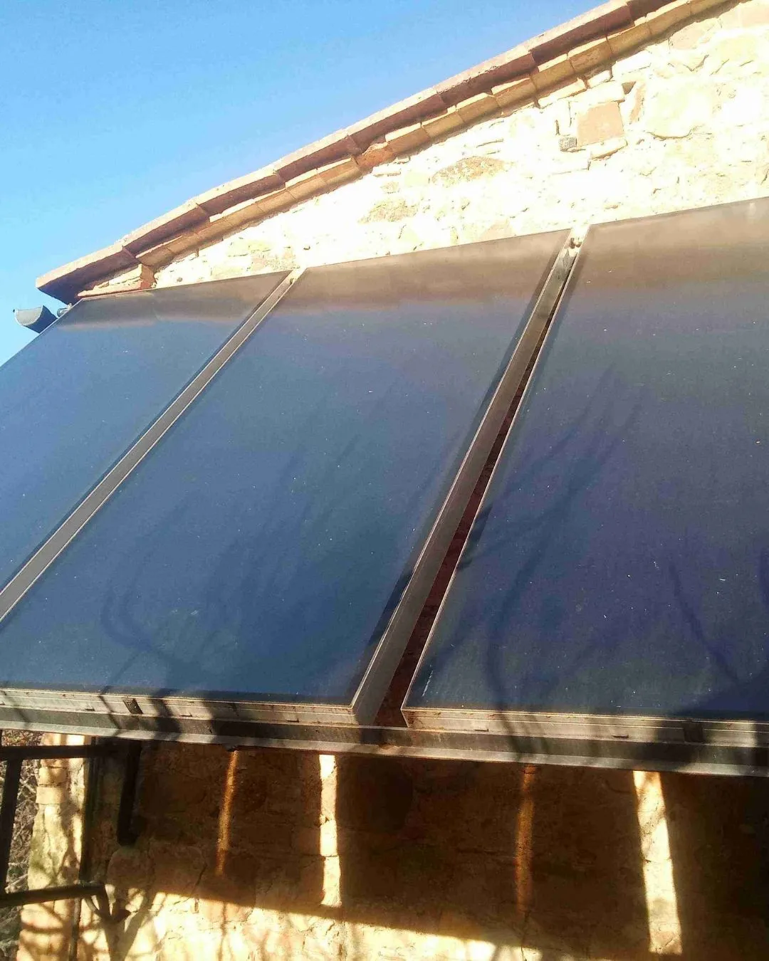 Due pannelli solari installati su un muro di pietra sotto un cielo sereno e azzurro.