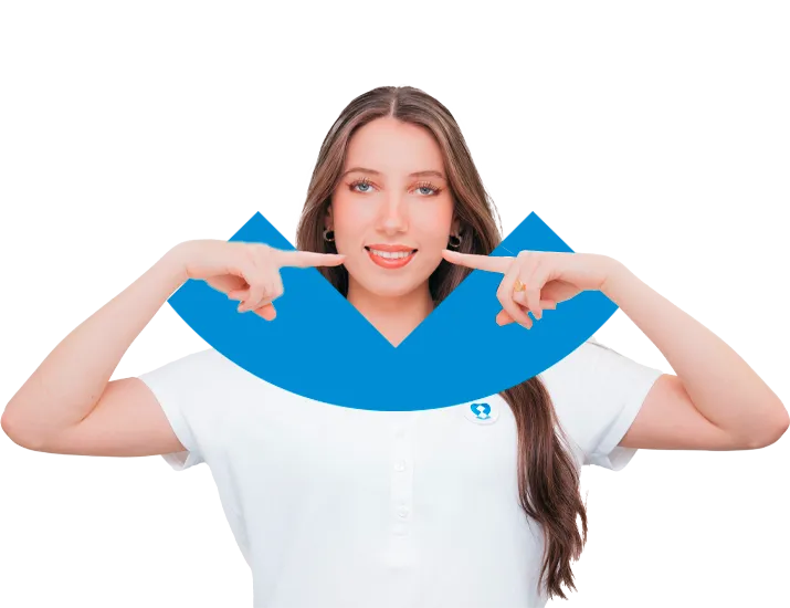 Jeune femme aux cheveux longs, portant un polo blanc avec un logo bleu, sourit et pointe ses index vers ses joues.