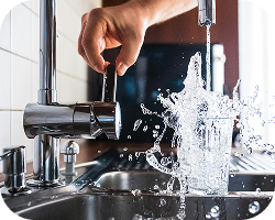 Hand taking drinkingwater from a regular kitchen tab. Tabwater