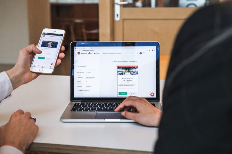 Zwei Personen vergleichen eine mobile und Desktop-Ansicht einer Webseite.