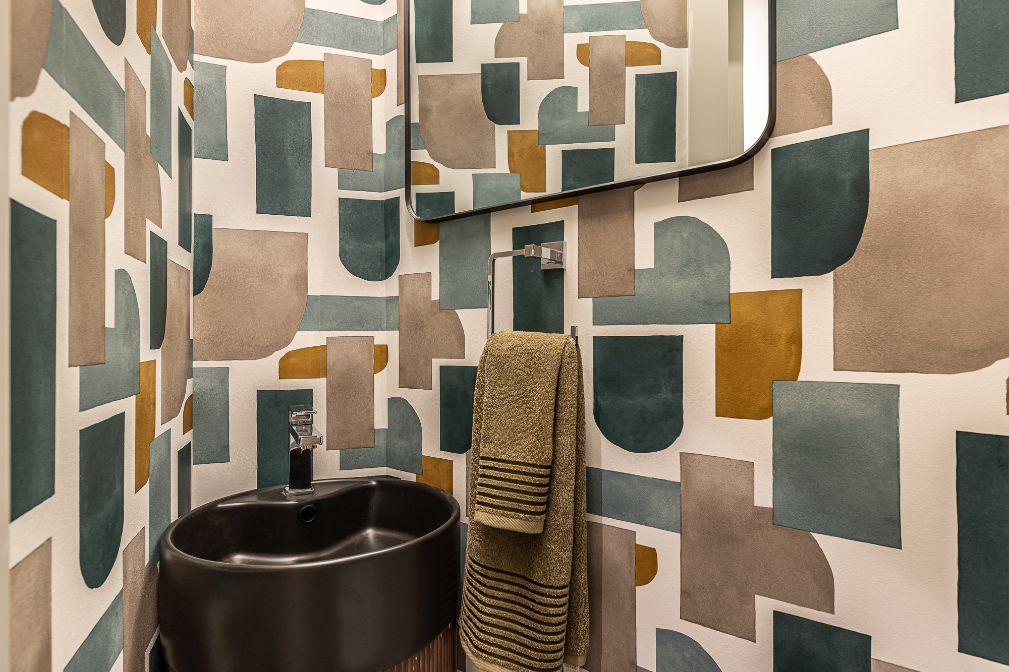 Aseo de cortesía con papel abstracto, lavabo negro y toalla verde