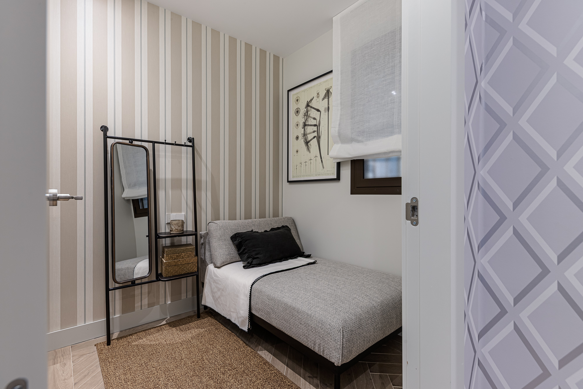Dormitorio auxiliar con papel de rayas, chaise longue y perchero con espejo