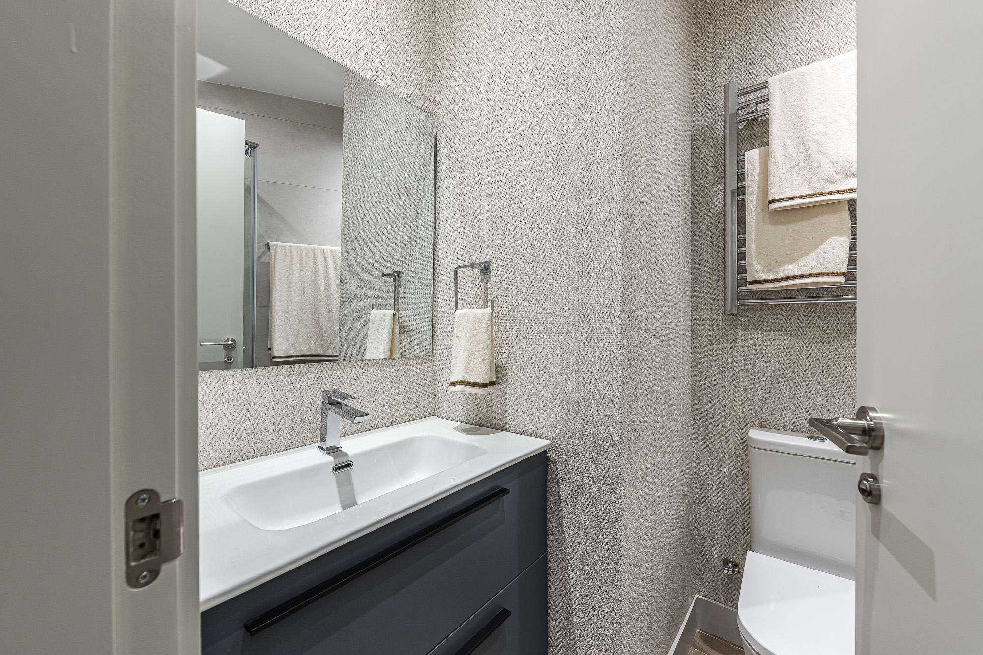 Baño con mueble azul, lavabo blanco, toallero y papel en espiga