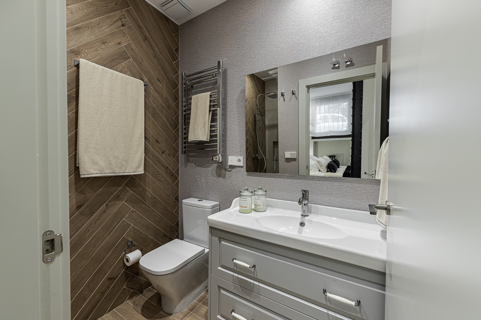 Baño con revestimiento de madera en espiga, inodoro y mueble blanco