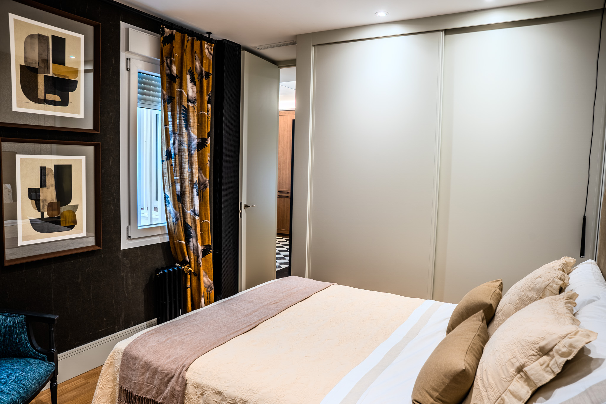 Dormitorio con armario corredero, cortina mostaza y suelo de madera
