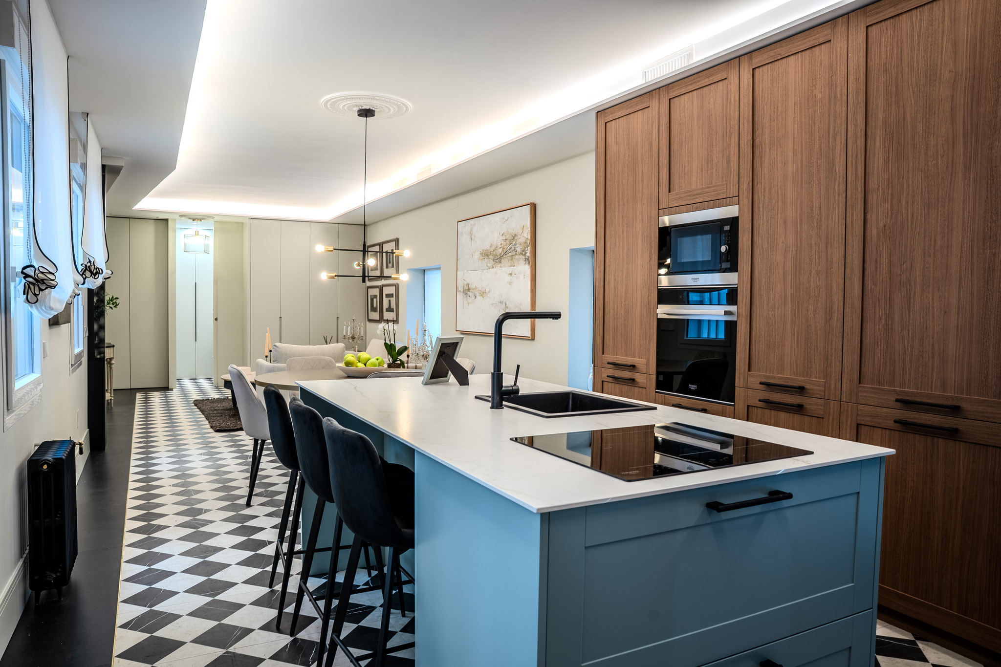 Isla de cocina azul con encimera clara, fregadero negro y frente de madera