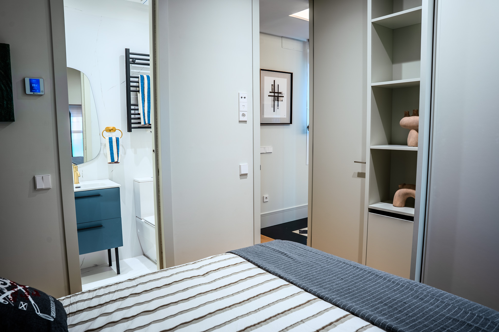 Dormitorio con paso al baño en azul y estantería a medida