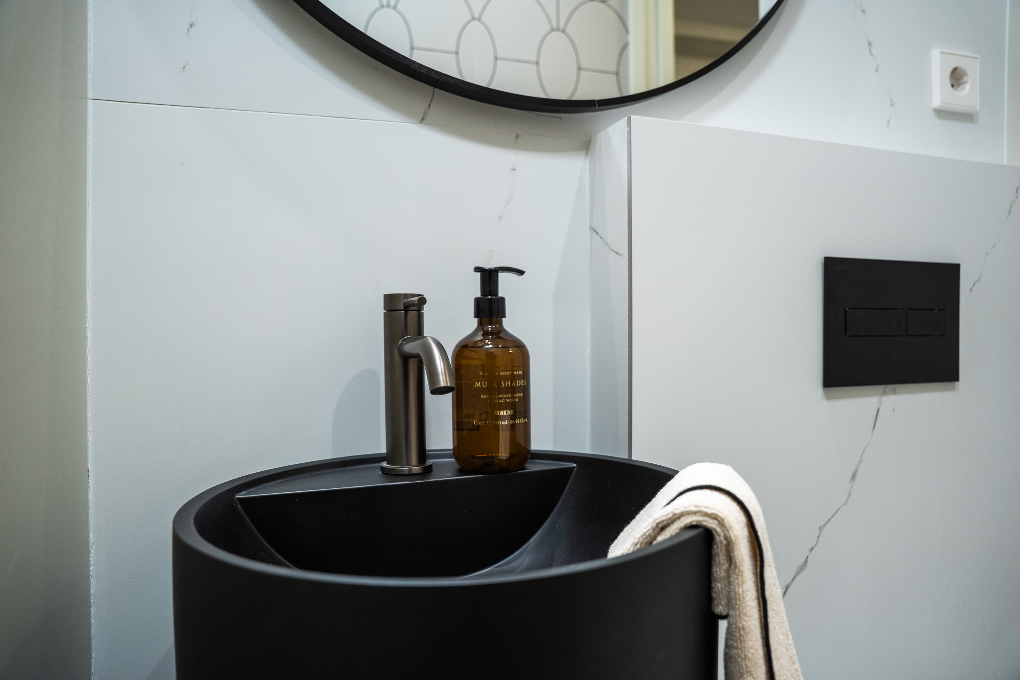 Aseo con lavabo negro, grifo en metal oscuro y espejo circular