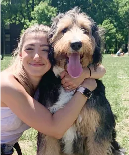 Siling client hugging their bernedoodle dog in a park.