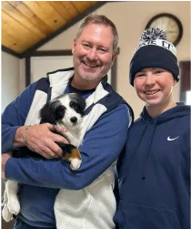Satisfied client with his son holding a bernedoodle puppy.