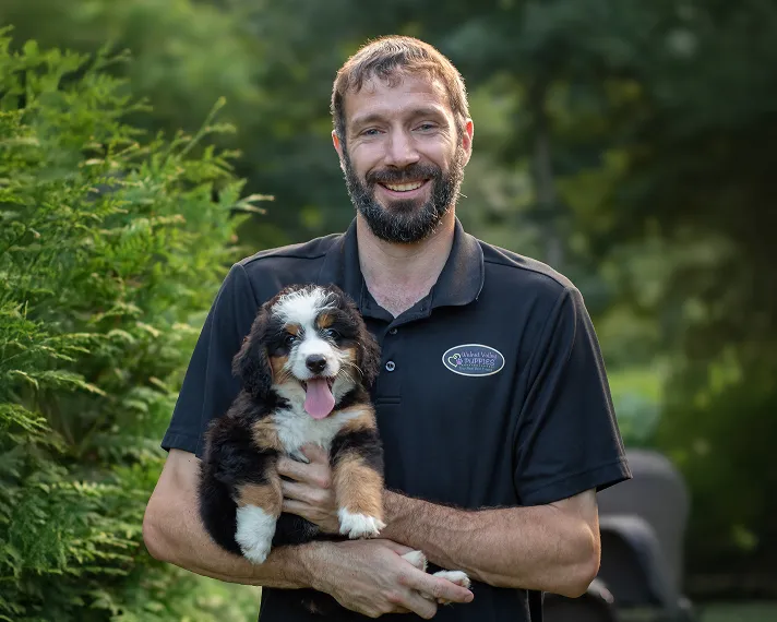 Javin smiling and holding a puppy 