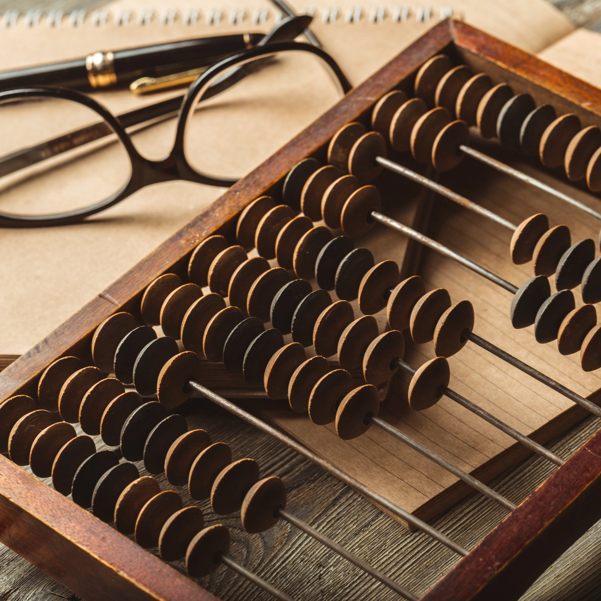 Image of a abacus with glasses and a pen on paper