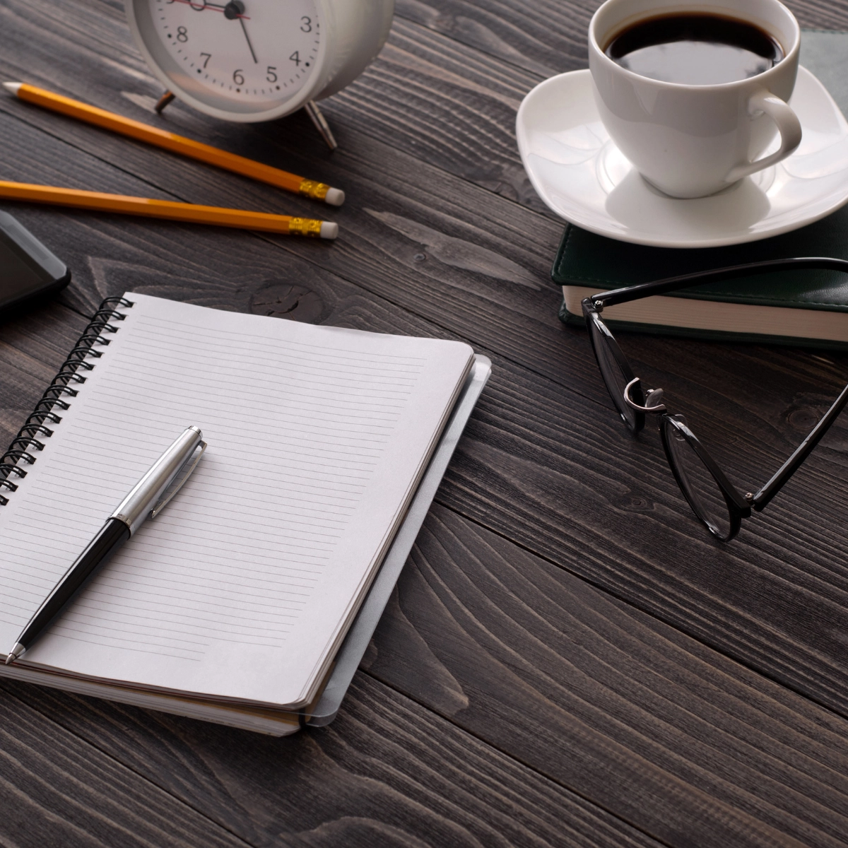 Image of a clean desk with a cup of coffee and a pad of paper and pen.