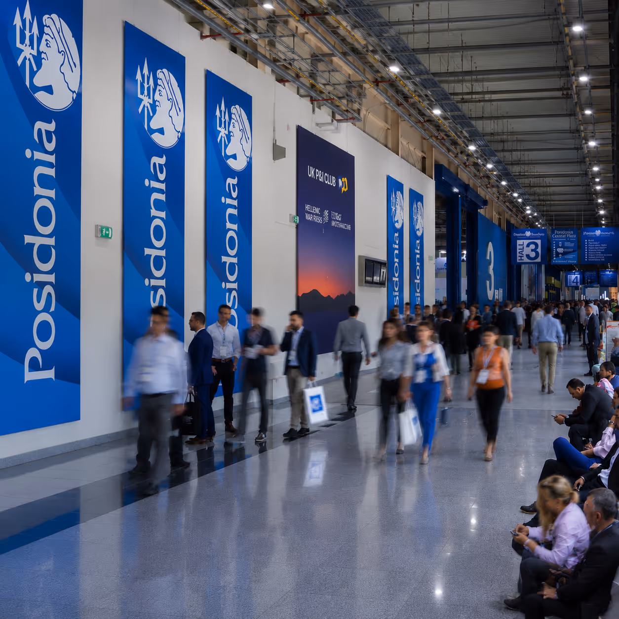 Busy convention hall with people walking and sitting near large blue Posidonia banners on the wall.