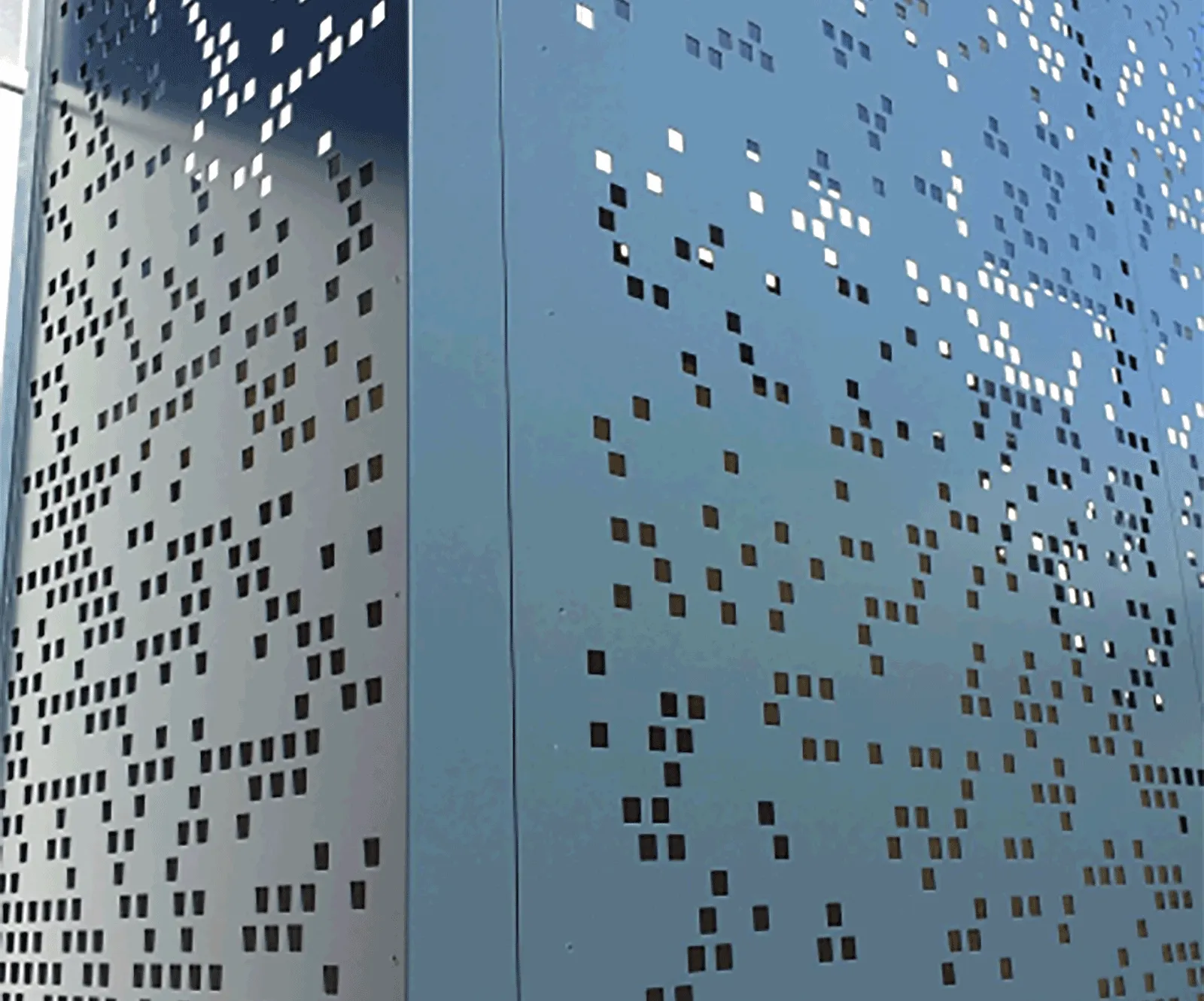Close-up of a blue metal facade with a custom pattern of perforated square holes.