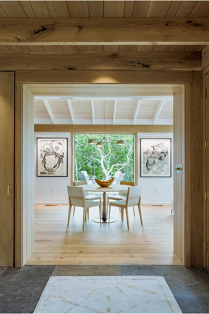 Round dining table and mid century chairs over looking screen porch with fire in the fireplace.