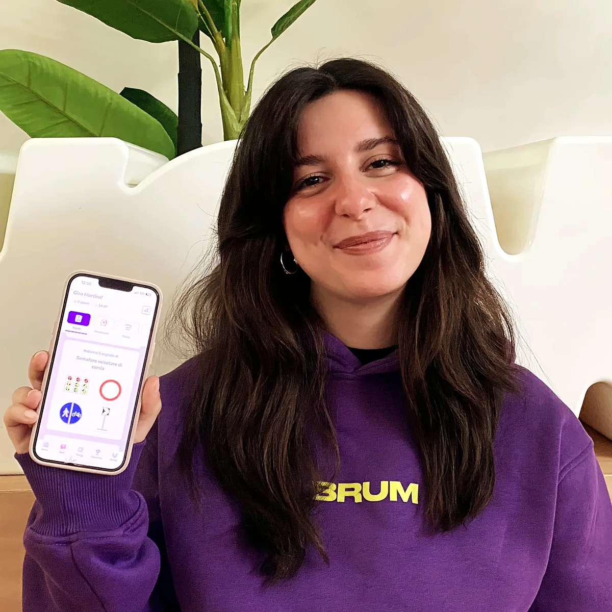 Ragazza con la felpa BRUM che mostra l'app BRUM sul telefono