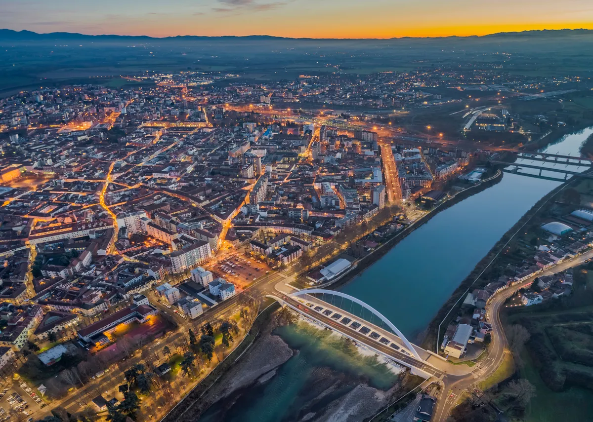 Veduta aerea notturna di Alessandria con il fiume e i ponti illuminati