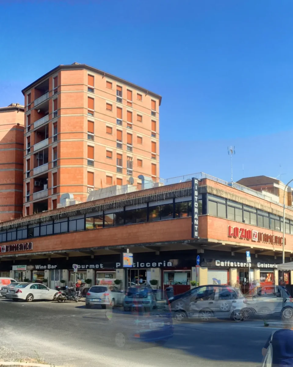 Roma, Talenti: la galleria di negozi sotto il palazzo rosso, con l'insegna del ristorante Lo Zio d'America