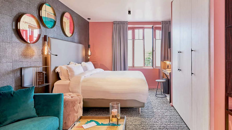 Charming hotel room in Brittany with contemporary design, powder pink walls, elegant furnishings and cosy atmosphere.