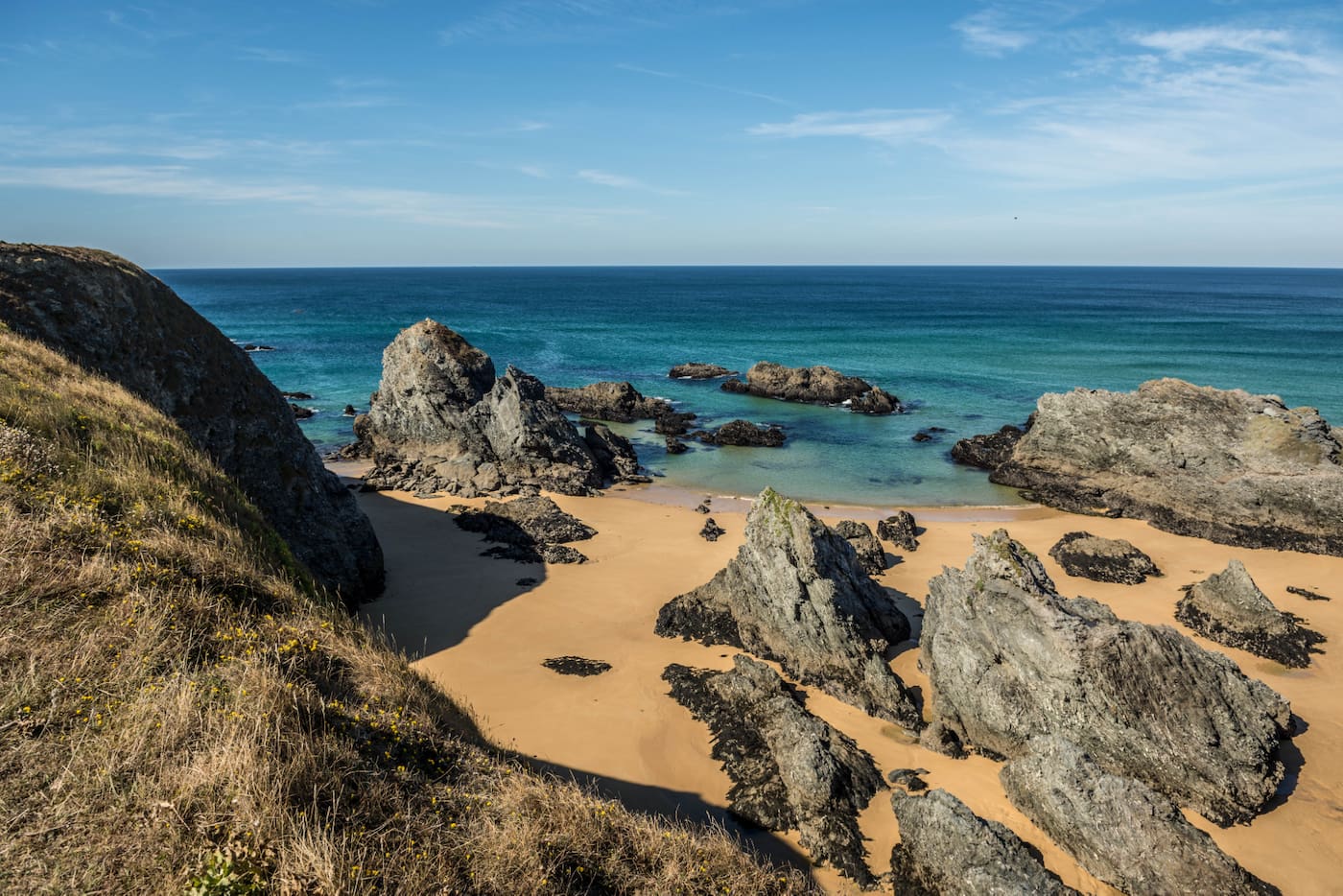 Vue sur la côte sauvage de Belle-Île-en-Mer avec ses falaises rocheuses, plage dorée et eaux turquoise, un cadre naturel préservé pour des vacances en Bretagne.