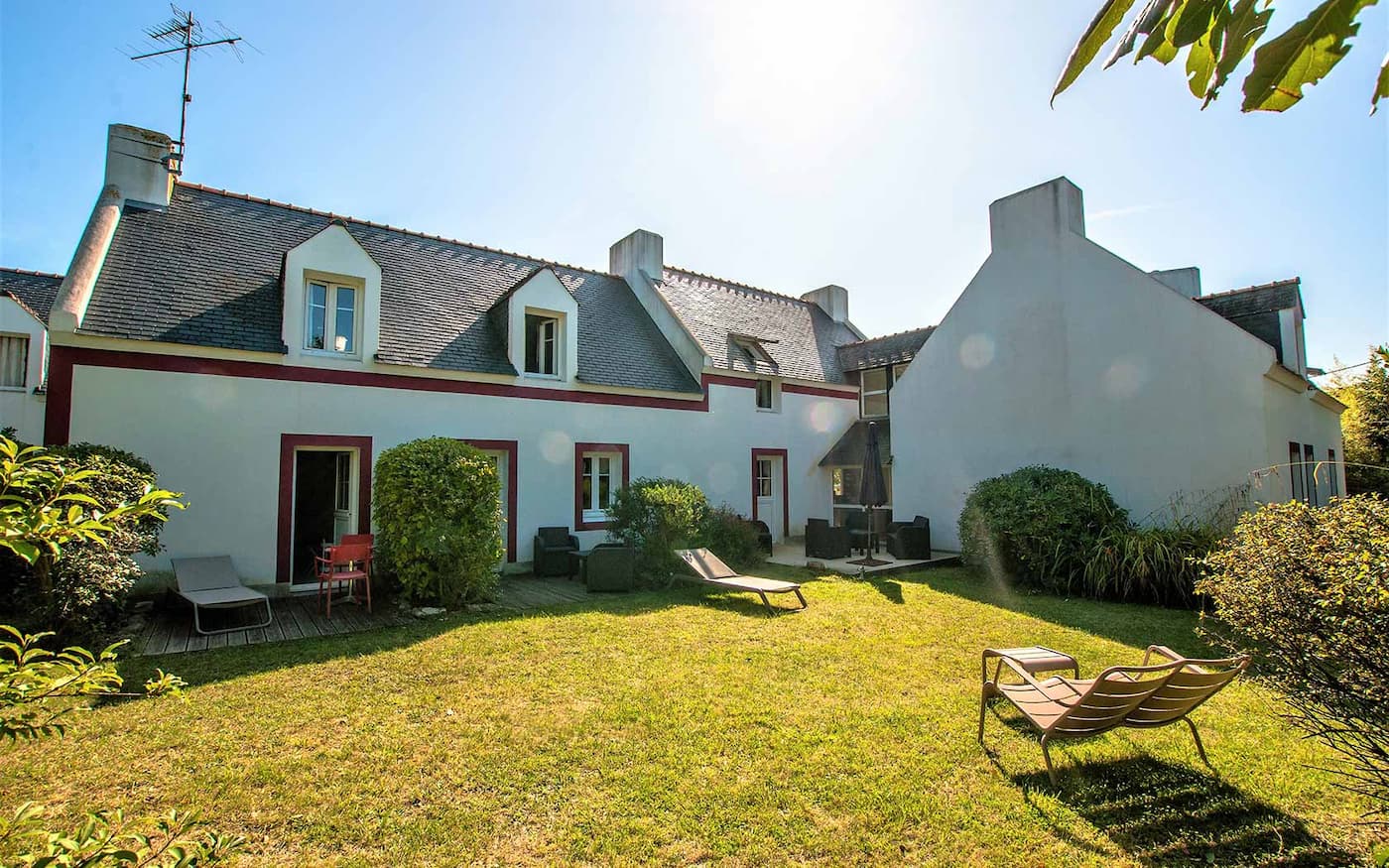 Façade ensoleillée de l’hôtel Le Clos Fleuri avec jardin verdoyant et transats, un hébergement de charme à Belle-Île-en-Mer
