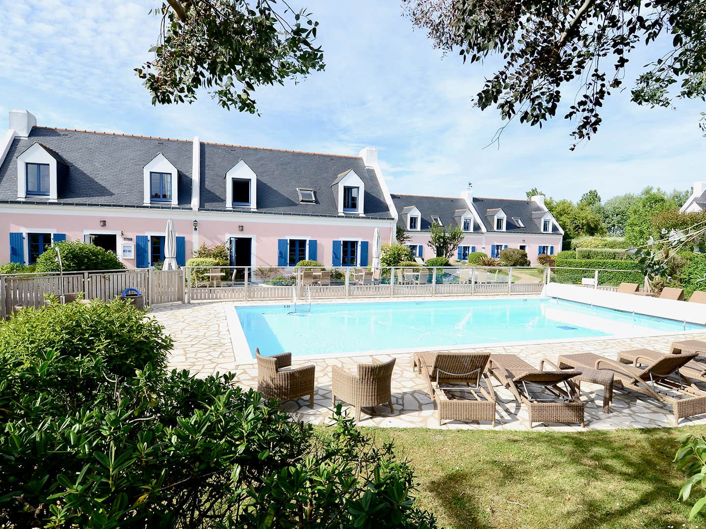 Vue sur la piscine extérieure et les bâtiments roses de l’hôtel La Désirade, un hôtel-spa-restaurant niché à Belle-Île-en-Mer
