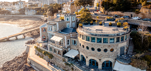 Vue aérienne de l’hôtel 5 étoiles Castelbrac à Dinard, installé à flanc de falaise avec terrasse sur la mer et accès direct à la plage